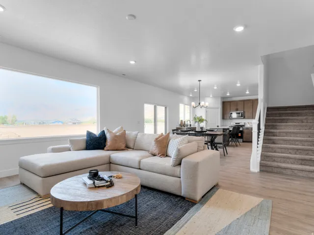 Expansive window, recessed lighting, wood-finish flooring, staircase with white newel posts, and dark wood-finish cabinetry