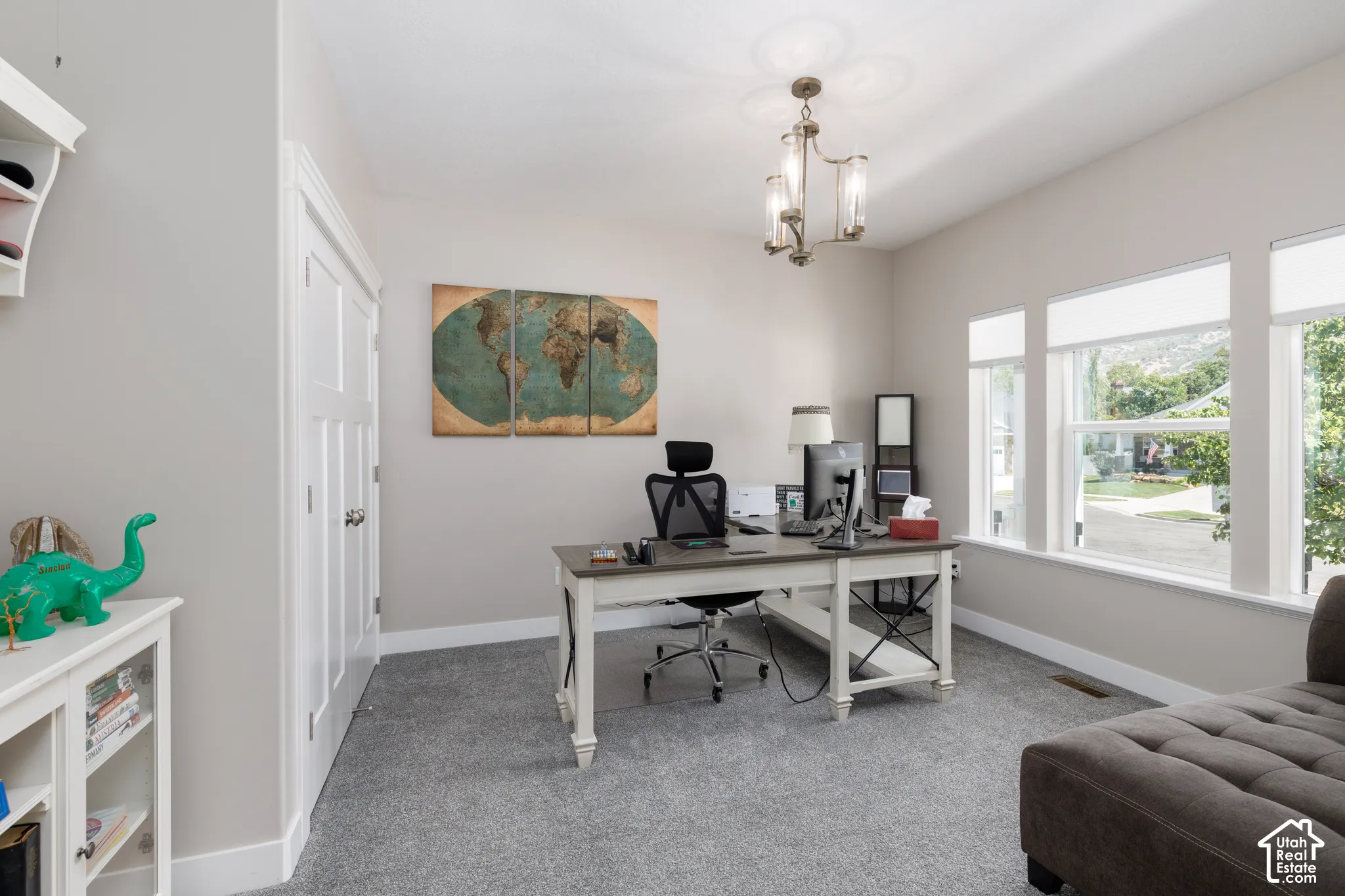 Recessed lighting, three large windows, a built-in shelf unit, and a chandelier with glass shades