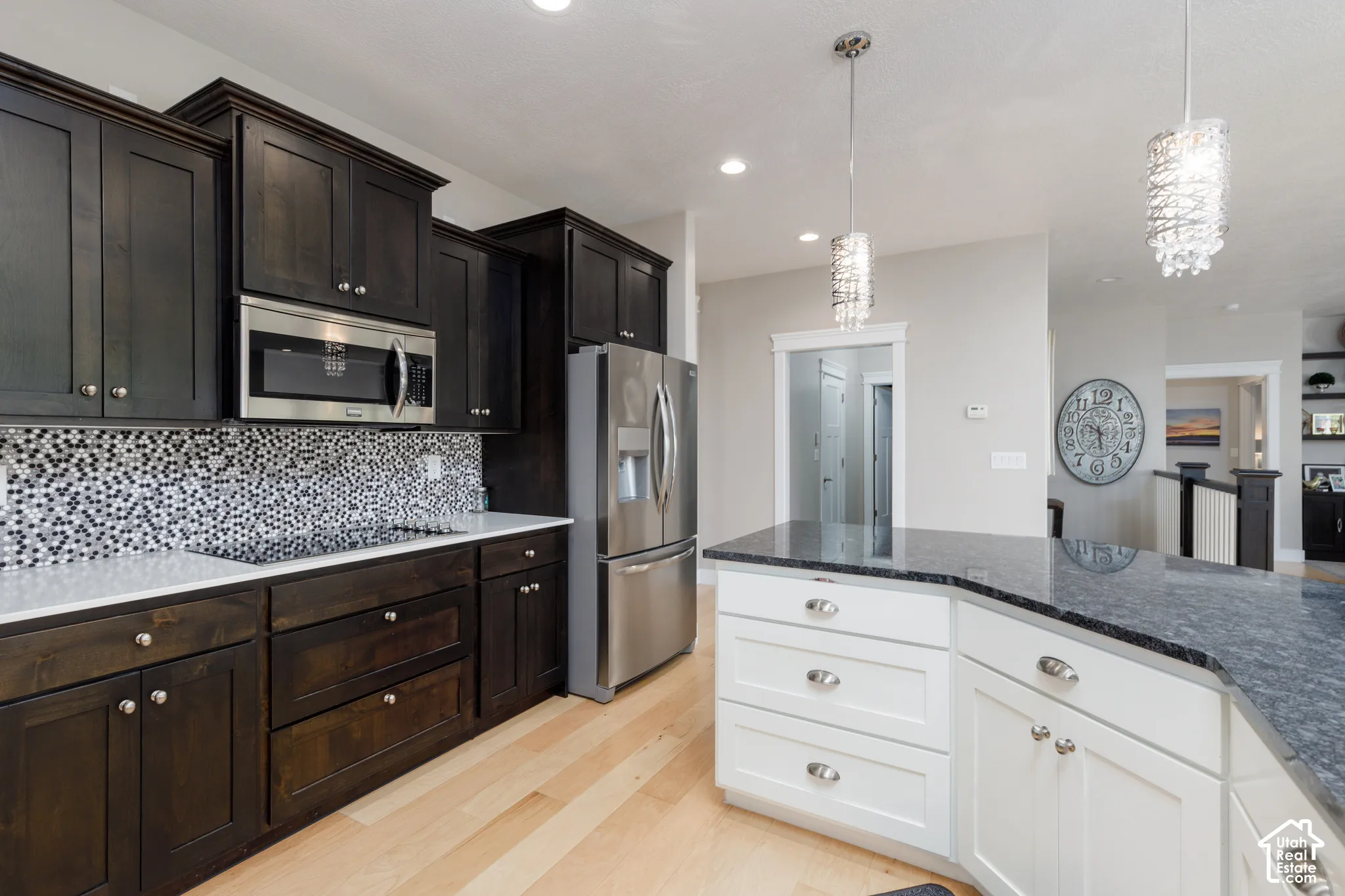 Kitchen featuring dark wood cabinetry, stainless steel appliances, a mosaic tile backsplash, and a central island with a contrasting countertop