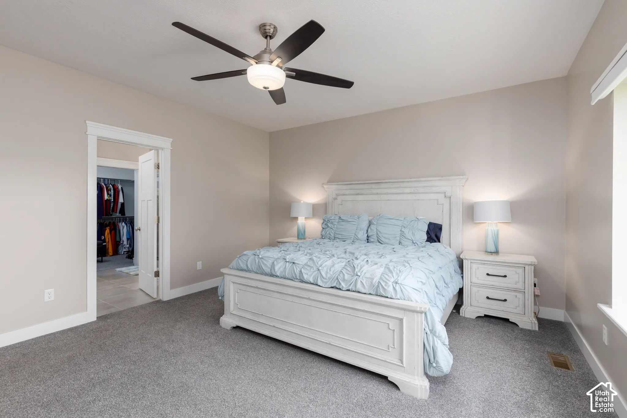 Carpeted bedroom featuring a ceiling fan, a window, and an entryway to a closet with built-in storage