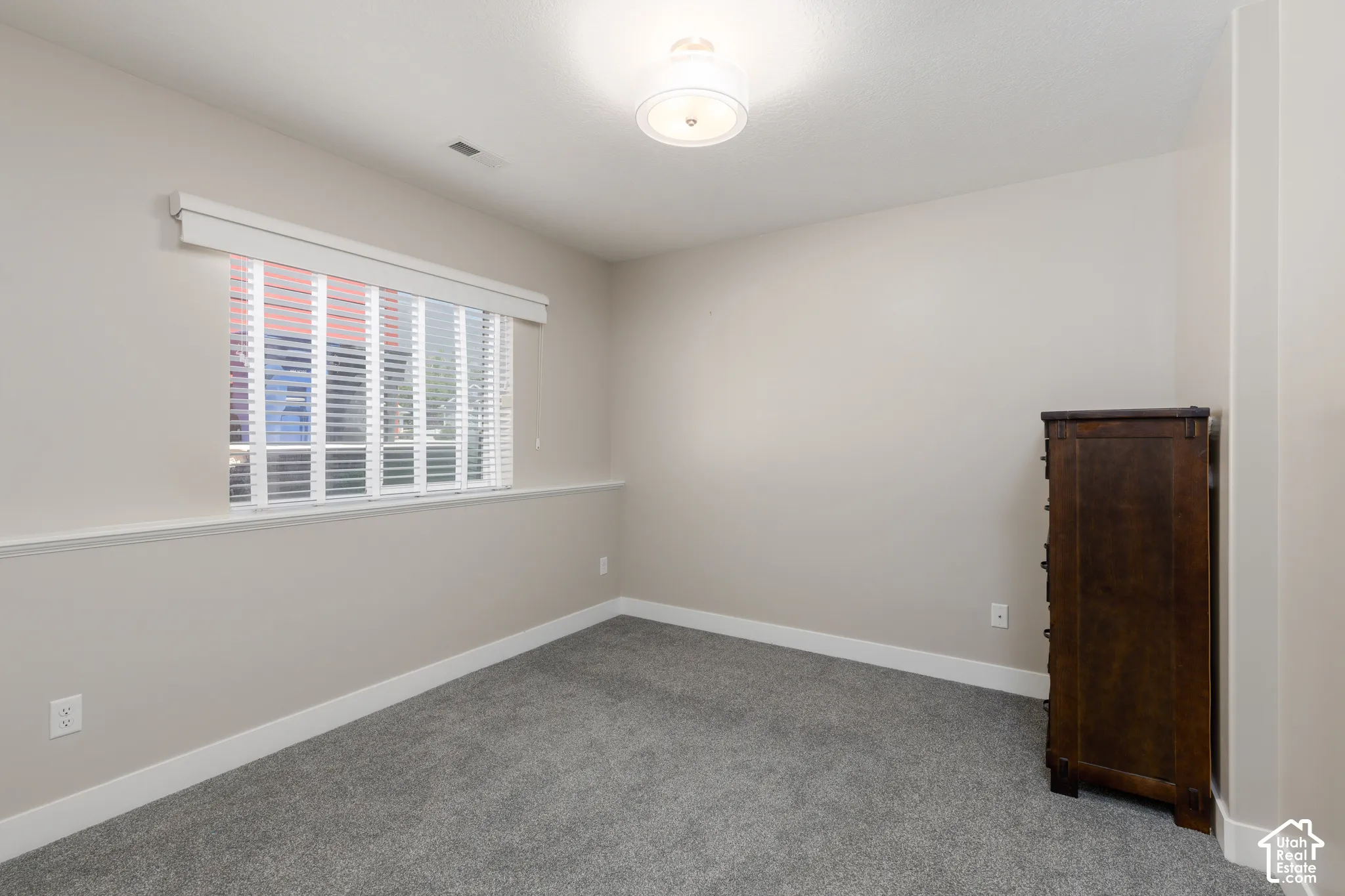 Recessed window with blinds, overhead flush-mount light fixture, and neutral wall tones