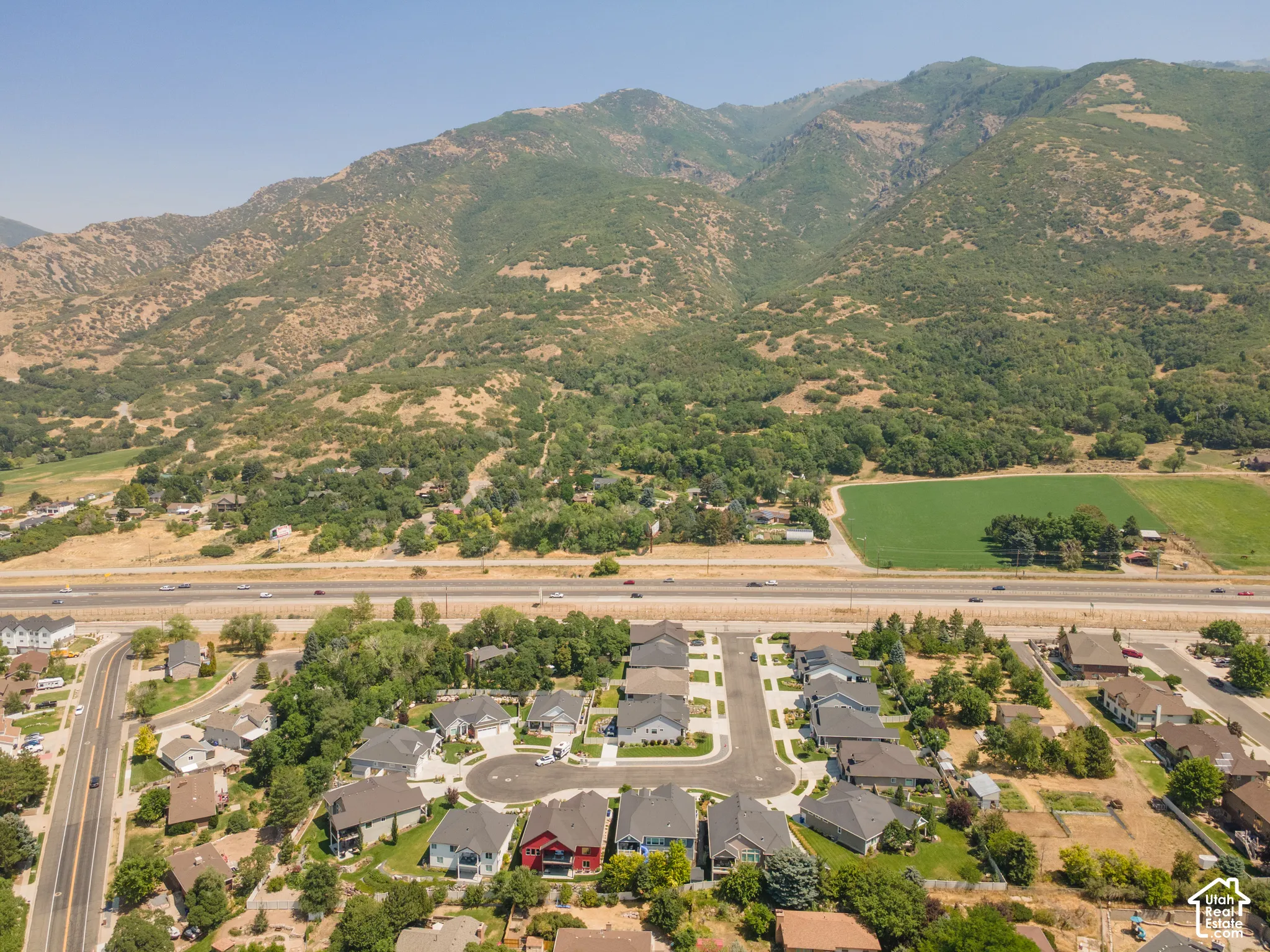 Aerial perspective featuring a residential cul-de-sac, multiple single-family homes, and a prominent mountain backdrop