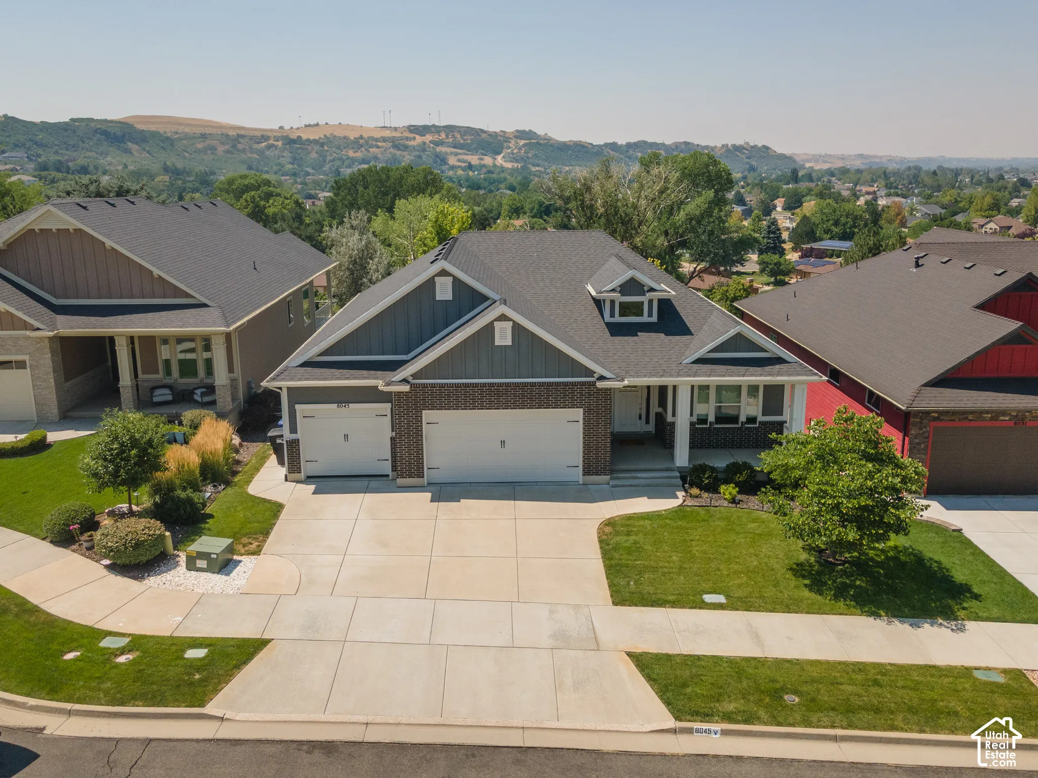 Front elevation featuring a dormer window, two-car garage, brick facade, and landscaping