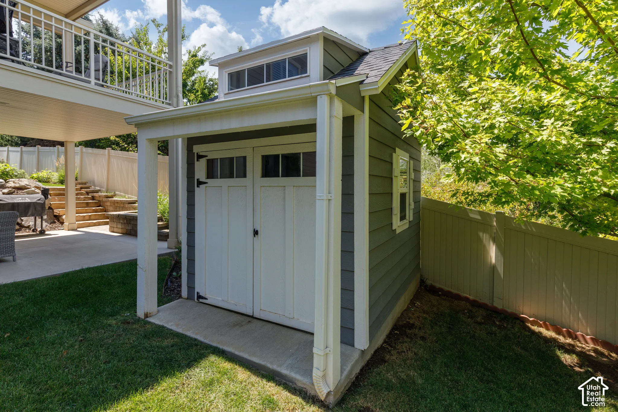 Storage shed with transom windows, double doors, exterior siding, and a concrete pad