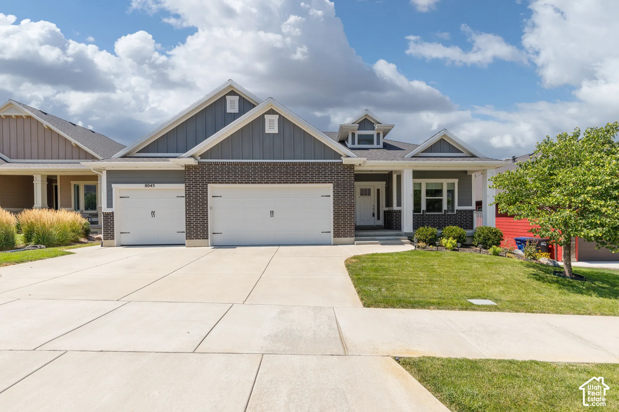 Exterior featuring brick and siding accents, a two-car garage, a concrete driveway, a covered entry, and a manicured lawn