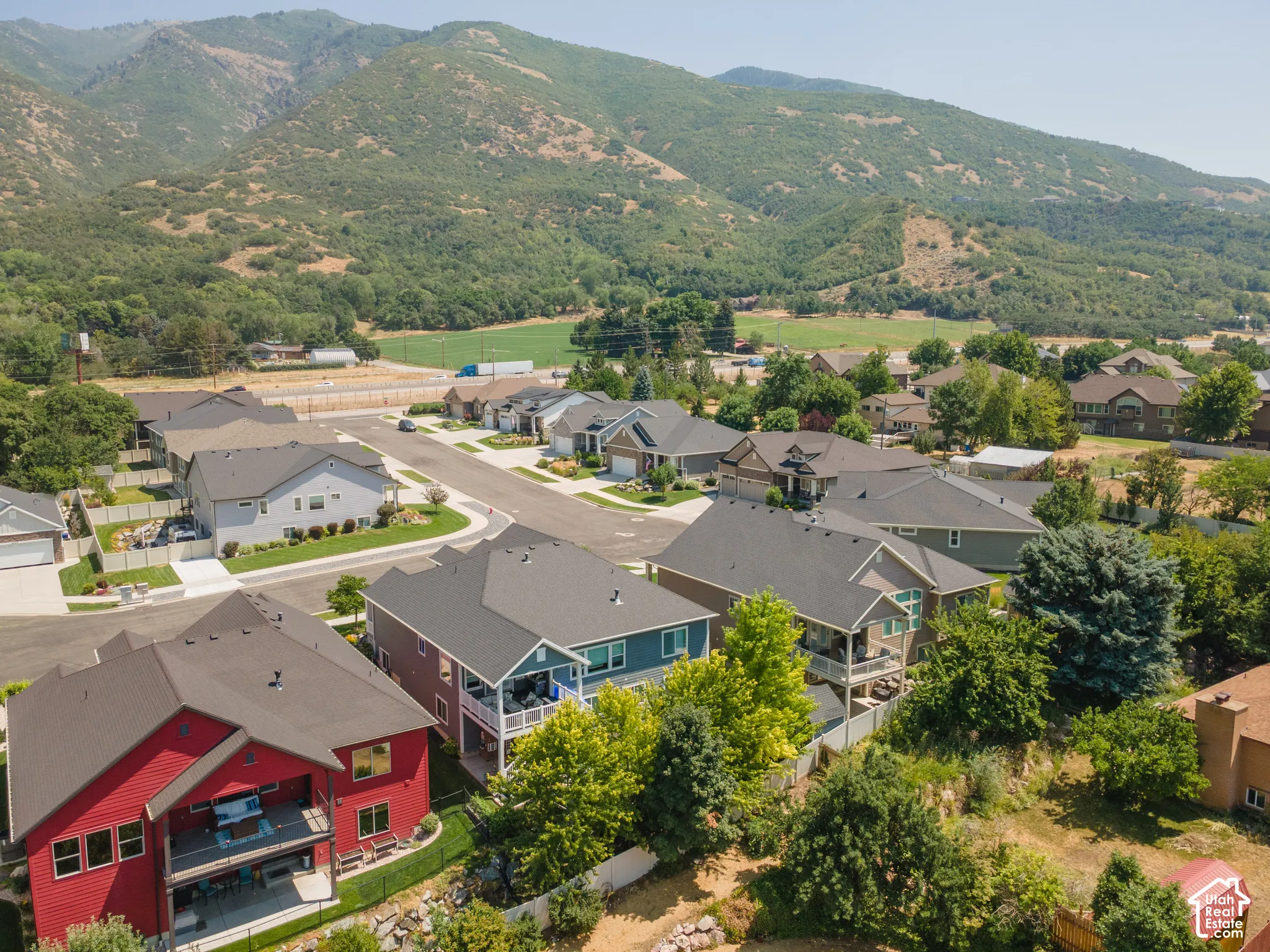 Residential street with paved roadways, established landscaping, and surrounding mountainous terrain