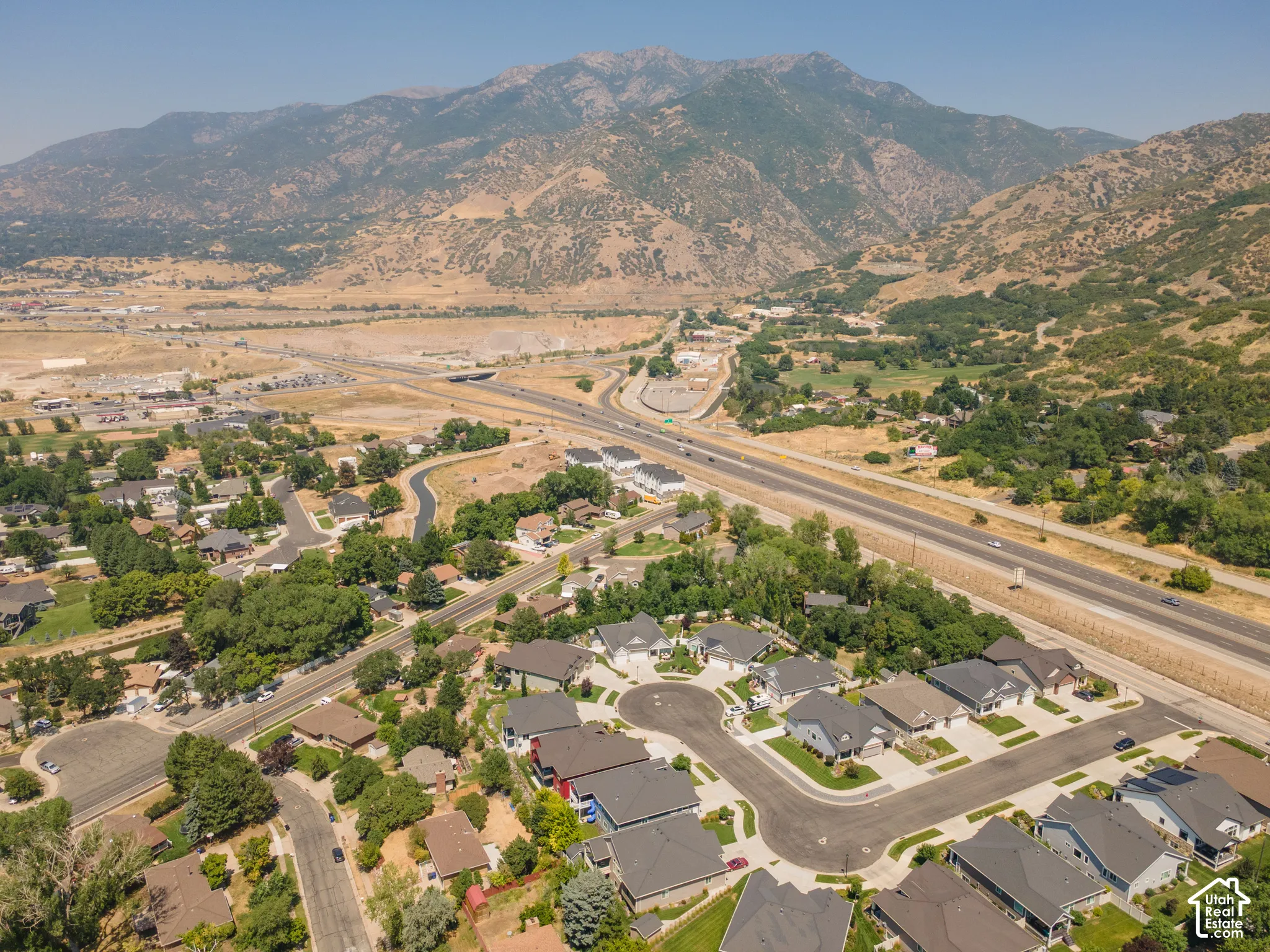 Residential neighborhood with a mountain backdrop, featuring paved roads and mature trees