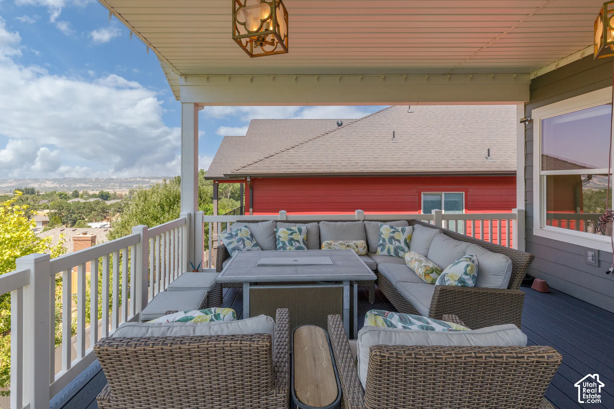 Covered outdoor deck with composite decking, white railing, and decorative overhead lighting