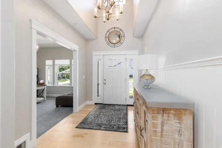 Two-story foyer with wood-finish flooring, a decorative chandelier, and wainscoting