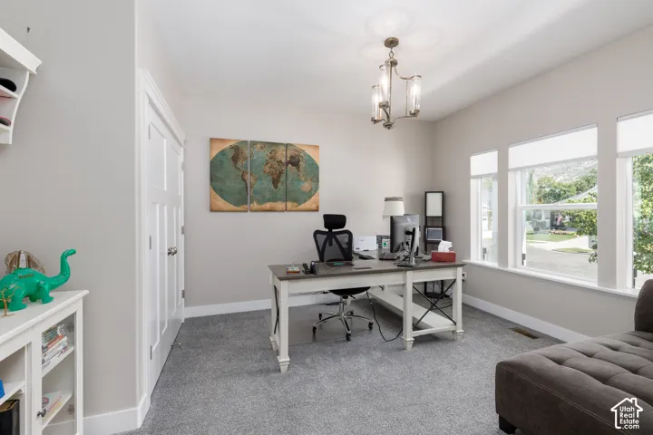 Recessed lighting, three large windows, a built-in shelf unit, and a chandelier with glass shades