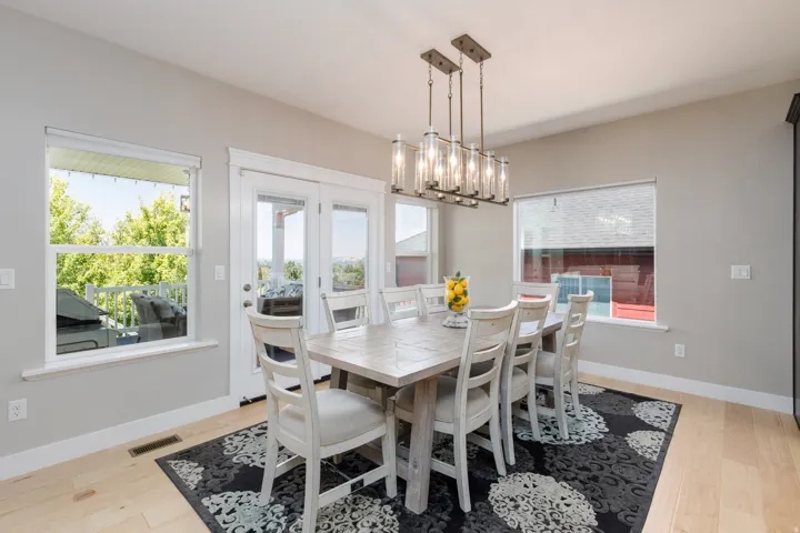 Wood-finish flooring with light gray walls, white trim, and a multi-light linear chandelier
