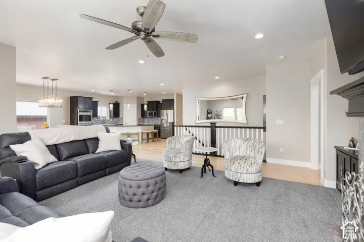 Open concept living space with recessed lighting, wood-finish flooring, and a fireplace with decorative screen