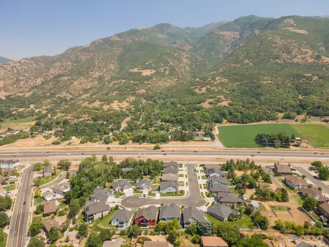 Aerial perspective featuring a residential cul-de-sac, multiple single-family homes, and a prominent mountain backdrop