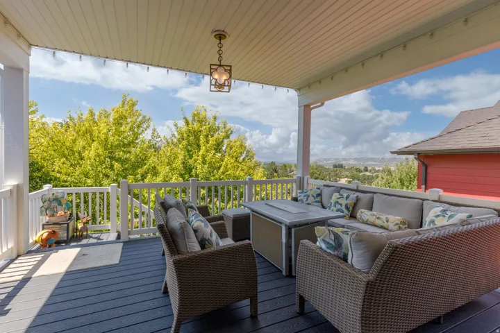 Covered patio featuring a dark composite deck, white railing, and a decorative pendant light fixture