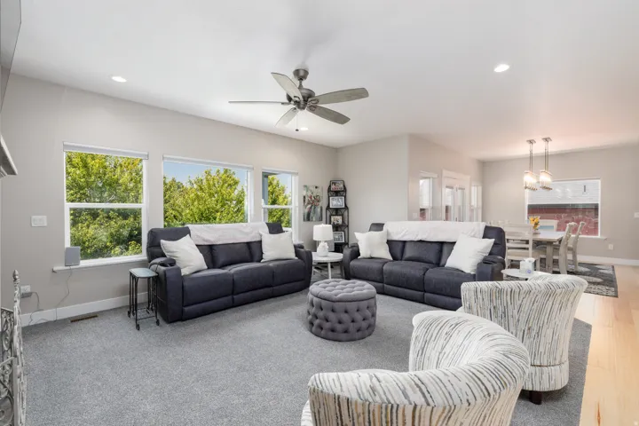 Spacious living area featuring light gray walls, recessed lighting, a ceiling fan, and carpeted flooring