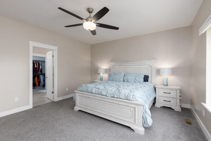 Carpeted bedroom featuring a ceiling fan, a window, and an entryway to a closet with built-in storage