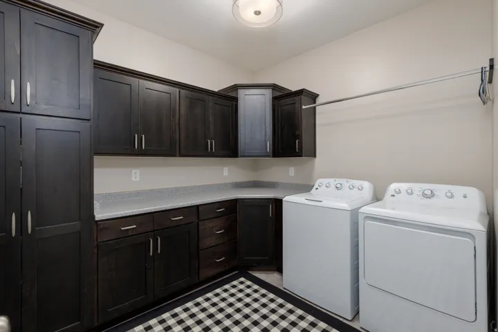 Dark wood-finish cabinetry, light-colored countertops, overhead lighting, and an installed hanging rod