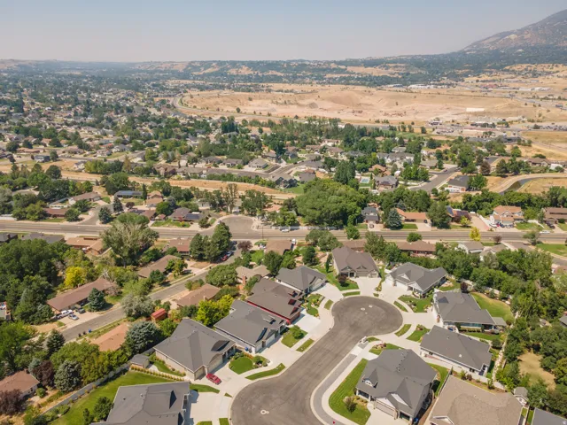 Aerial perspective showcasing a residential cul-de-sac, surrounded by established landscaping and a distant mountainous backdrop