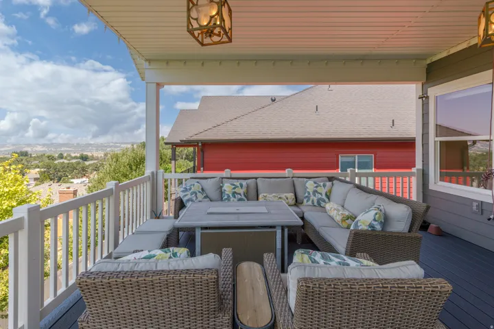 Covered outdoor deck with composite decking, white railing, and decorative overhead lighting