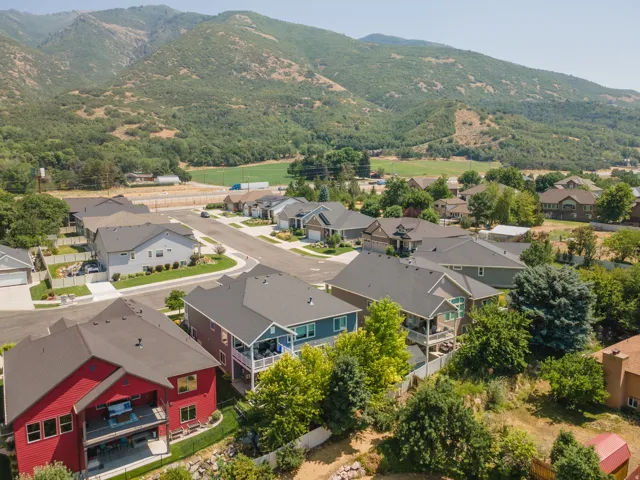 Residential street with paved roadways, established landscaping, and surrounding mountainous terrain