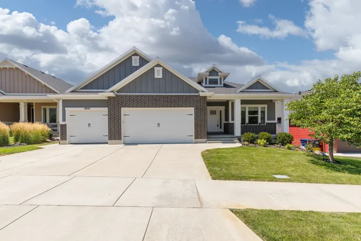Exterior featuring brick and siding accents, a two-car garage, a concrete driveway, a covered entry, and a manicured lawn