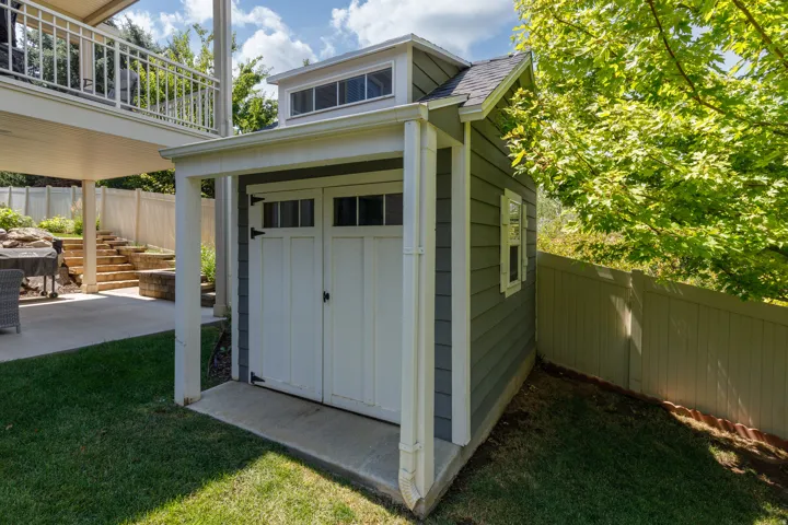 Storage shed with transom windows, double doors, exterior siding, and a concrete pad