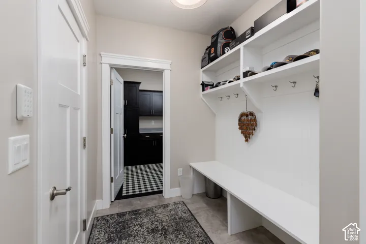 Built-in storage bench with open shelving, wall-mounted hooks, and beadboard paneling