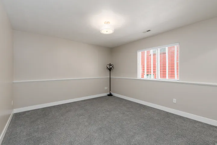 Carpeted flooring, neutral wall color, crown molding detail, white window blinds, and a flush mount ceiling light