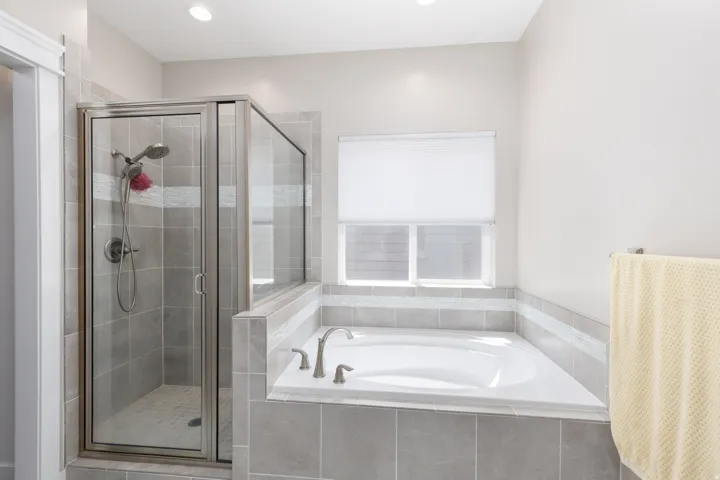 Walk-in shower with clear glass enclosure and tile surround
