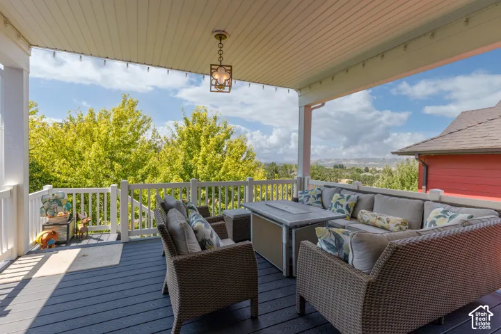 Covered patio featuring a dark composite deck, white railing, and a decorative pendant light fixture
