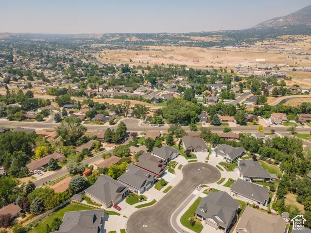 Aerial perspective showcasing a residential cul-de-sac, surrounded by established landscaping and a distant mountainous backdrop