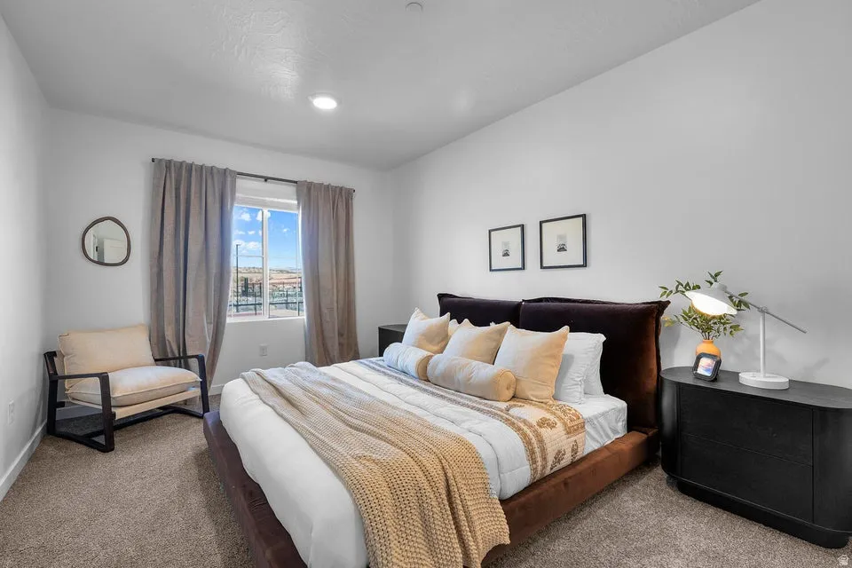 Plush carpet flooring complements a window with neutral drapes and a recessed ceiling light