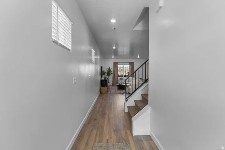 Wood-finish flooring, recessed lighting, and a staircase with a black metal railing