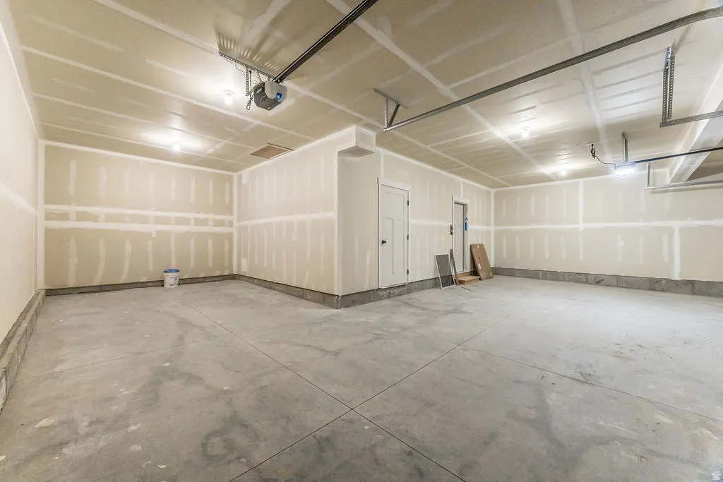 Spacious garage with exposed drywall, concrete flooring, and an overhead garage door opener
