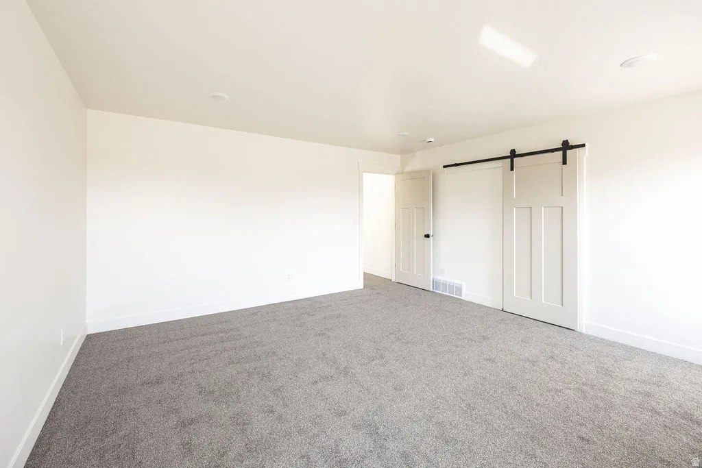 Spacious room with plush gray carpeting, white walls, and a recessed ceiling light