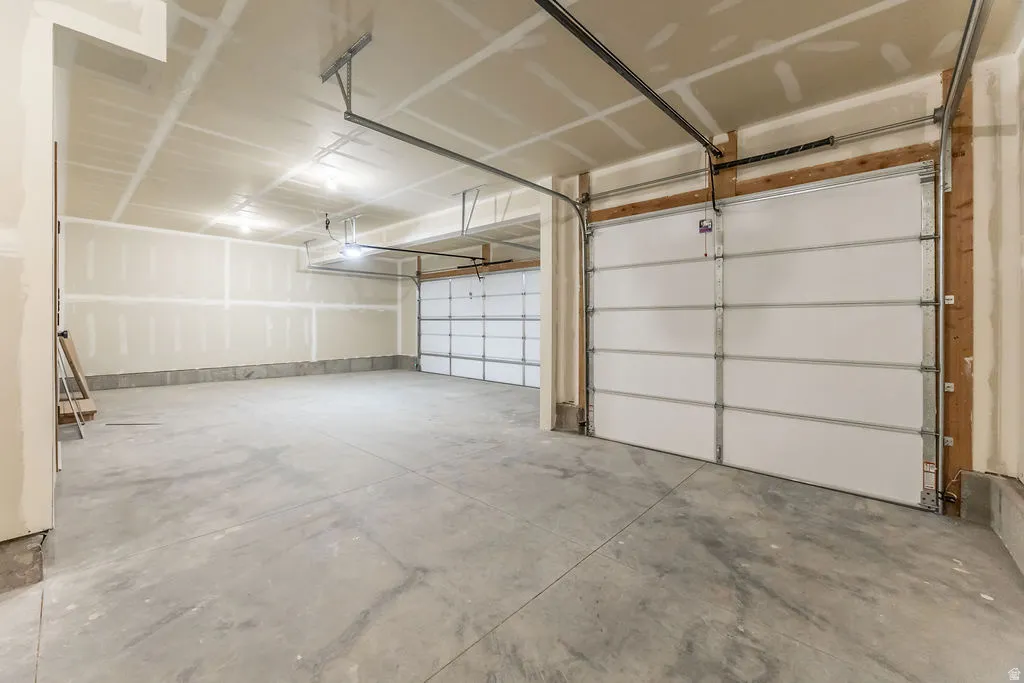 Spacious garage with multiple overhead doors, concrete flooring, and exposed ceiling joists