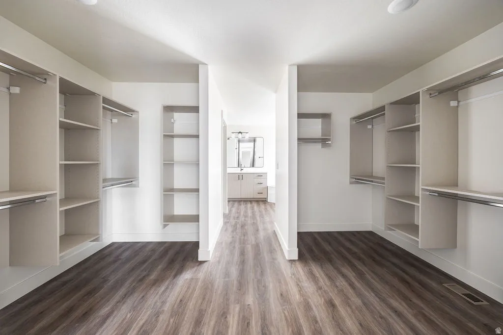 Walk-in closet with extensive built-in shelving, hanging rods, and wood-finish flooring