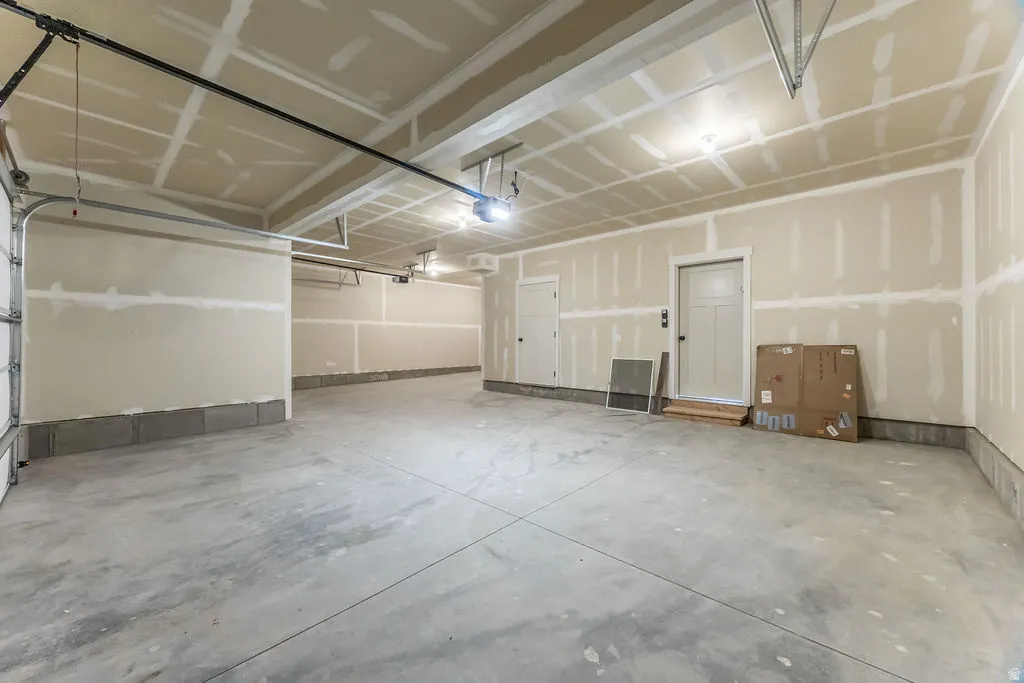 Concrete flooring with exposed drywall and flush-mounted ceiling lighting