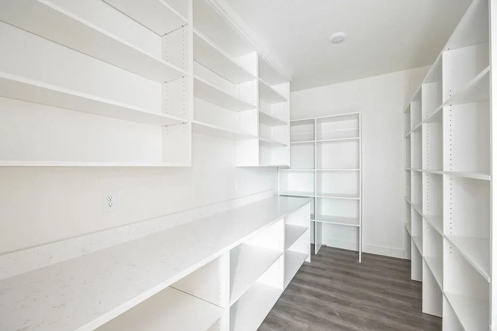 Extensive white built-in shelving, white countertop, and wood-finish flooring