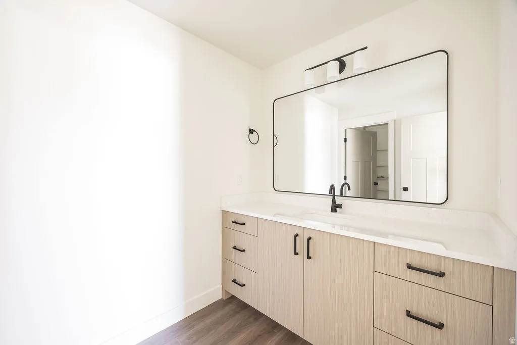 Wood-finish vanity with matte black hardware, integrated rectangular sink, stone-finish countertop, and a sleek black-framed mirror