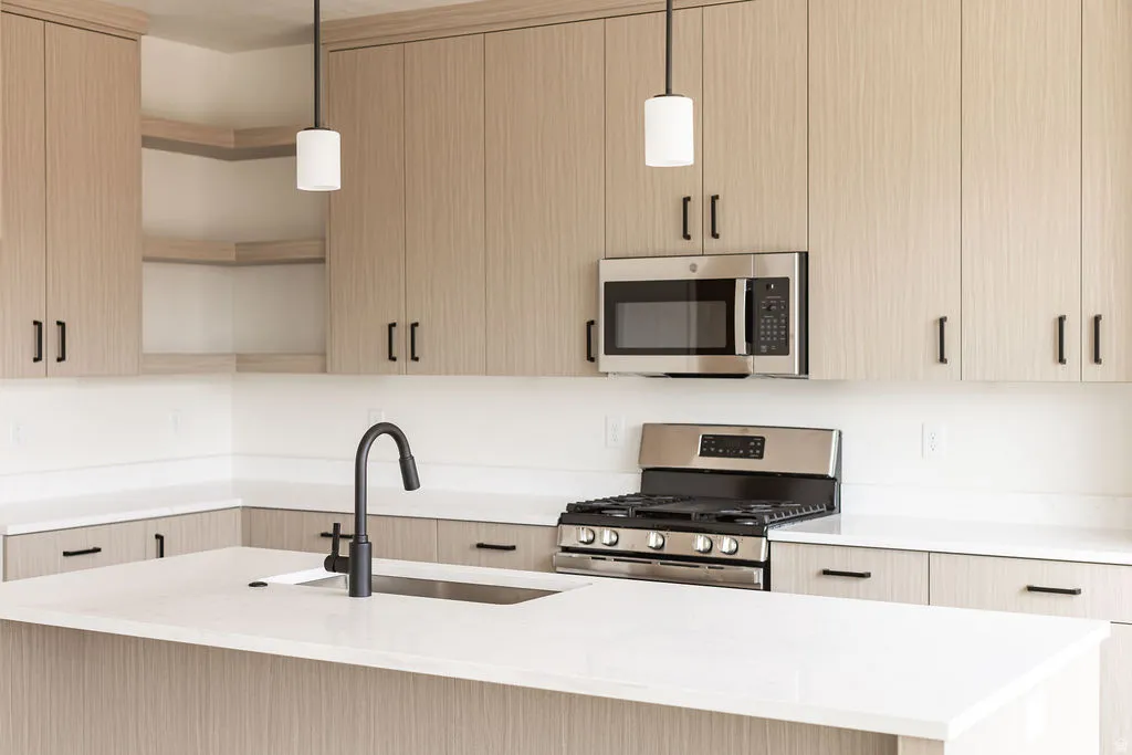 Light wood-finish cabinetry with black hardware, stainless steel appliances, white countertops, and a black gooseneck faucet