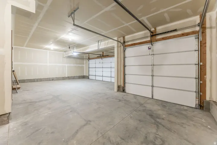 Spacious garage with multiple overhead doors, concrete flooring, and exposed ceiling joists