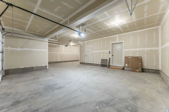 Concrete flooring with exposed drywall and flush-mounted ceiling lighting
