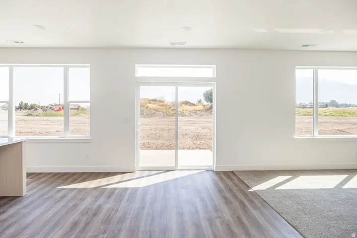 Bright interior with multiple windows, glass sliding door, and wood-finish flooring