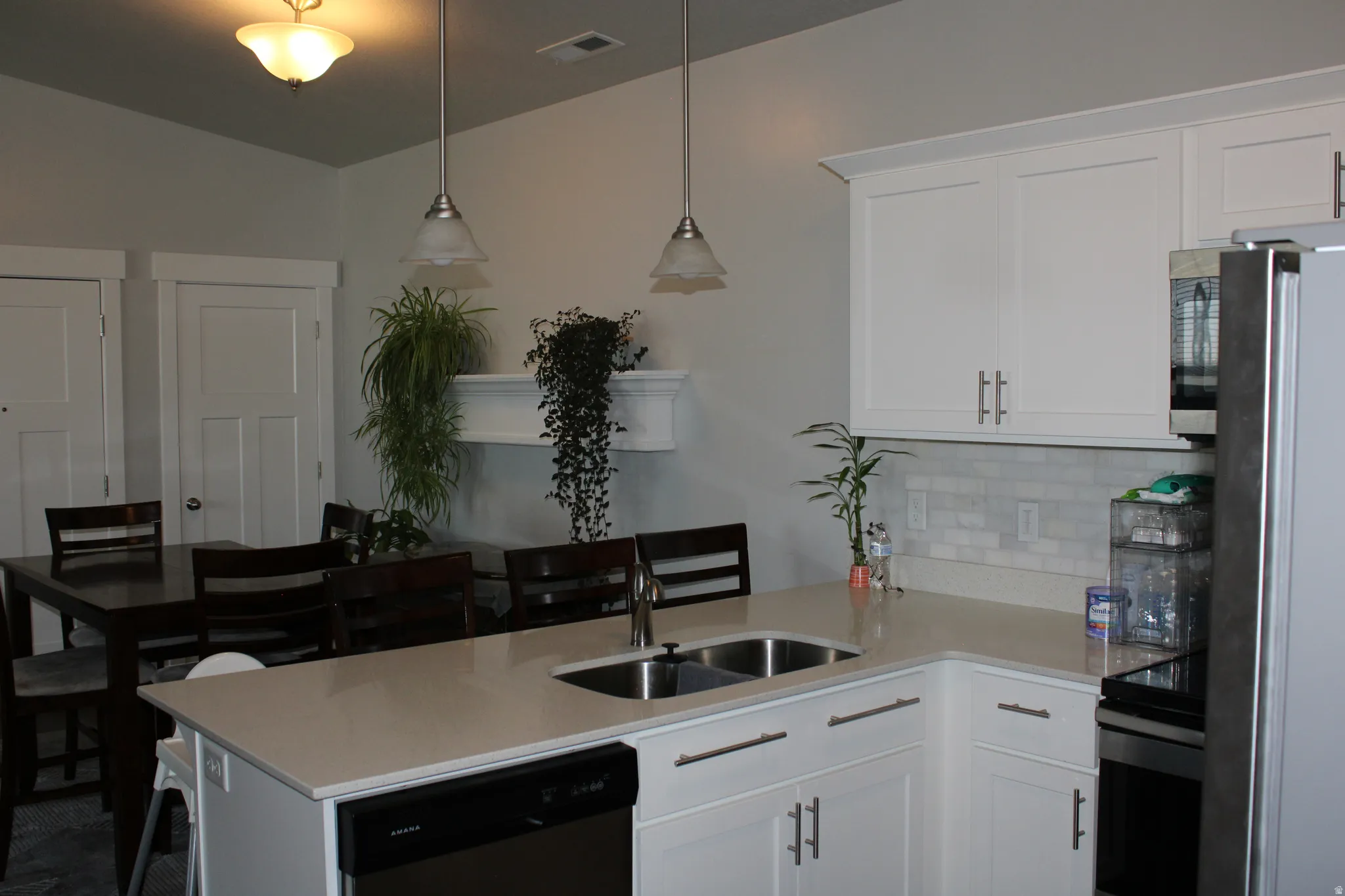White cabinetry with brushed nickel pulls, light-toned countertops, and a subway tile backsplash