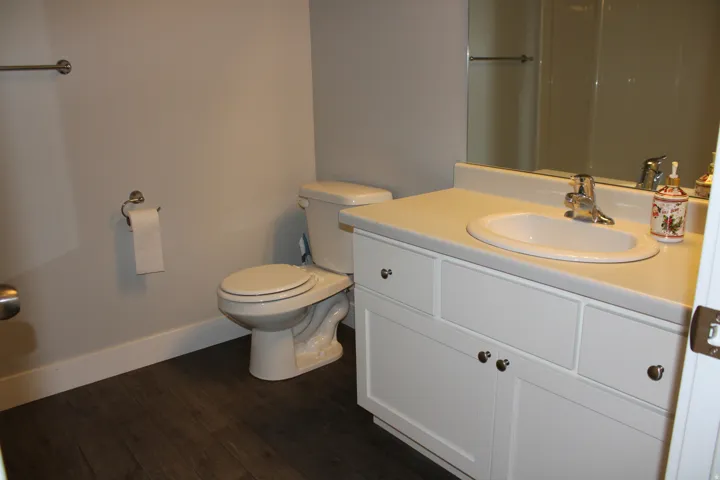 White vanity with an integrated sink, polished chrome faucet, and expansive wall mirror