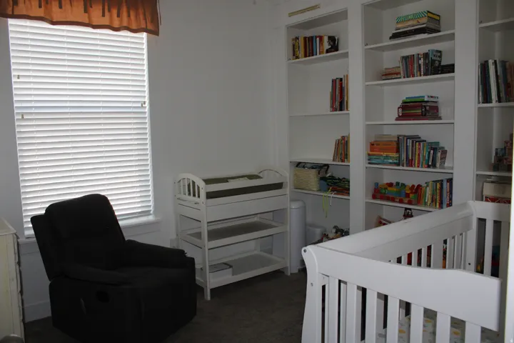 Recessed window with blinds, expansive built-in shelving, overhead lighting fixture