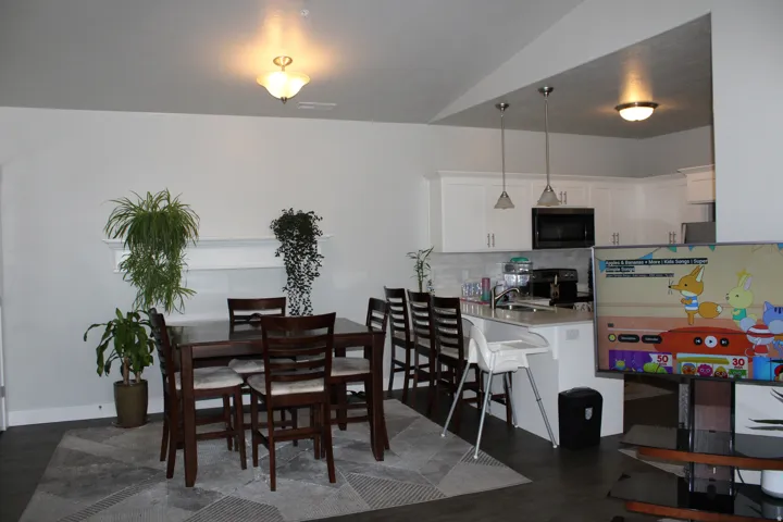Open-concept living space with dark wood-finish flooring, white walls, and a built-in wall shelf