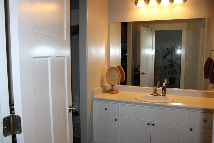 Vanity featuring an integrated sink, polished chrome faucet, white cabinetry, and a full-width mirror