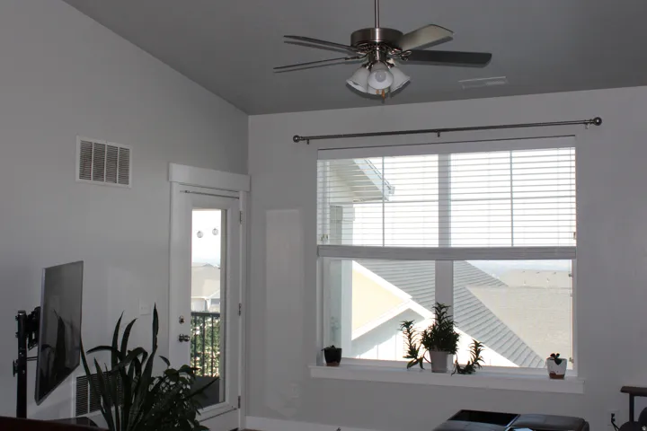 Vaulted ceiling, ceiling fan with integrated lighting, glass-paneled door, large window with blinds, and white trim throughout